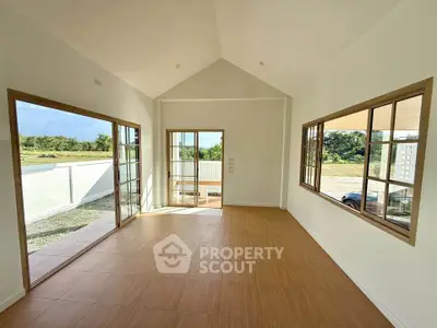 Spacious sunlit room with large windows and scenic views, perfect for modern living.