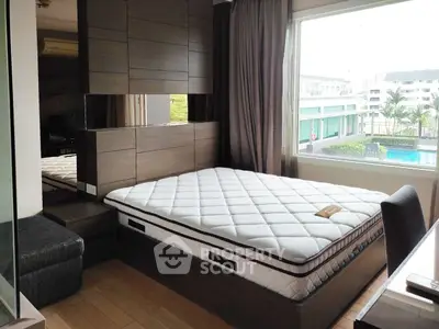 Modern bedroom with large window offering pool view, featuring stylish wood paneling and comfortable mattress.