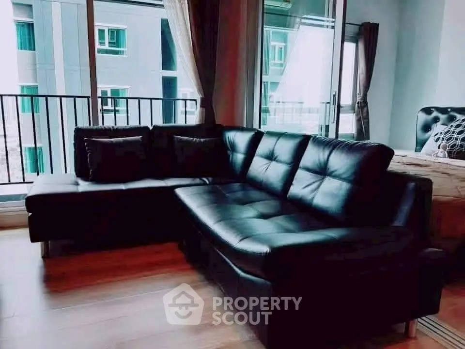 Stylish living room with black leather sofa and large windows offering natural light.