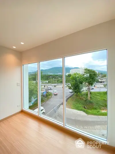 Spacious and bright corner unit with large windows offering a panoramic view of the serene landscape and urban horizon, perfect for a tranquil living experience.