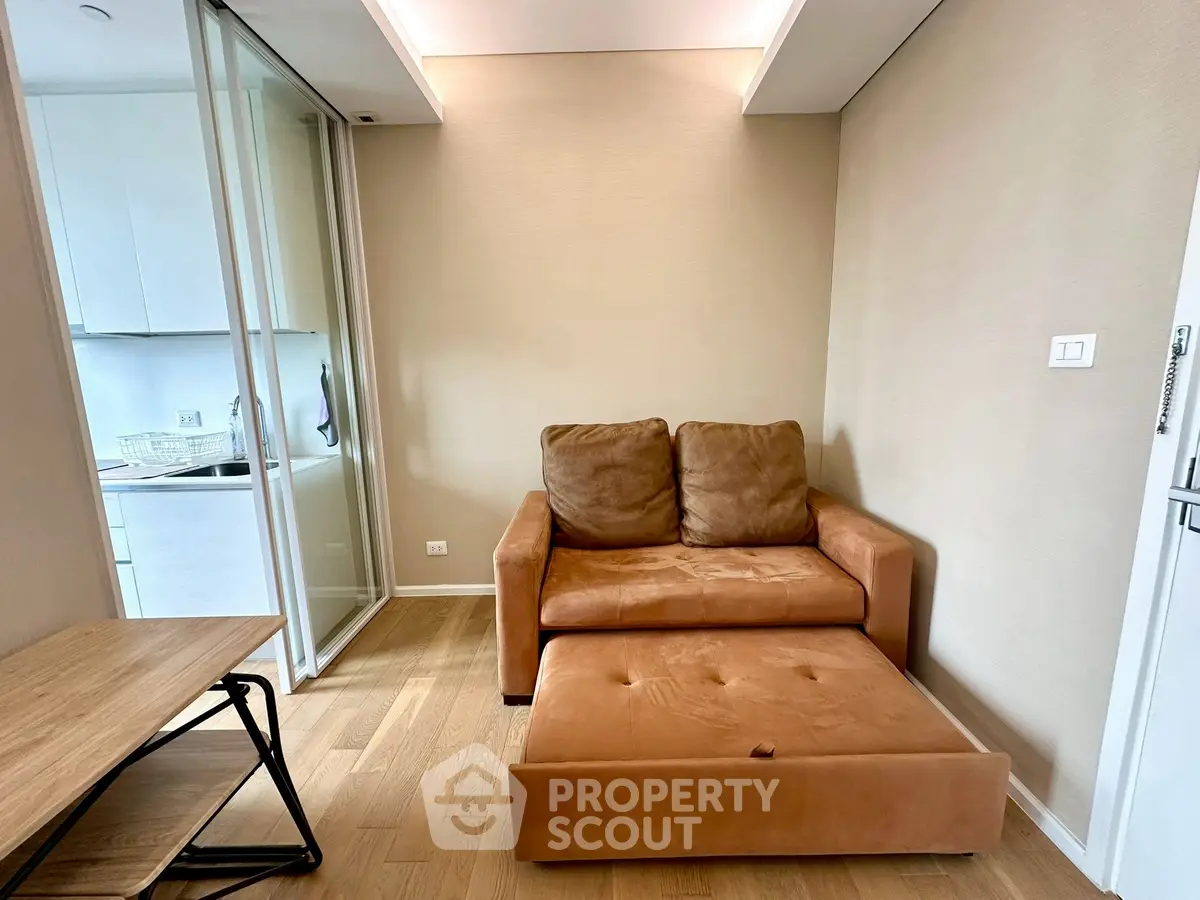 Cozy living area with a pull-out sofa and modern kitchen view, perfect for compact urban living.