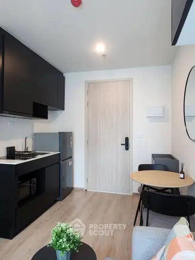 Modern compact kitchen with sleek black cabinets and cozy dining area