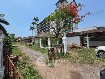 Charming rustic property with lush greenery and a modern building backdrop, perfect for serene living.