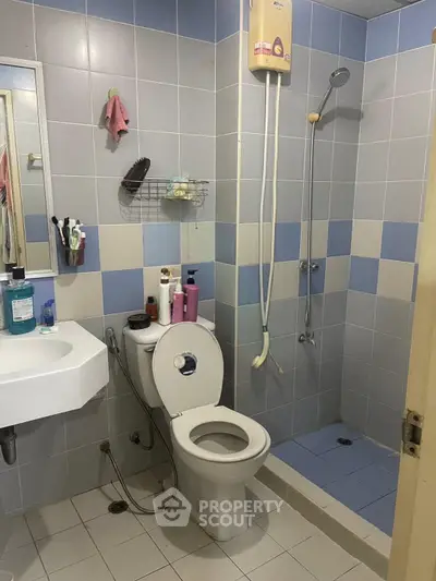 Modern bathroom with shower and toilet in a tiled setting, featuring essential amenities.