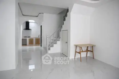 Modern minimalist interior with sleek kitchen and staircase, featuring glossy white tiles and wooden accents.