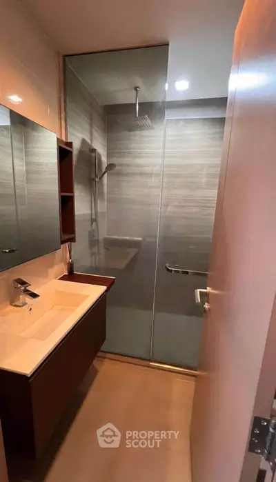 Modern bathroom with glass shower and sleek vanity in contemporary apartment.