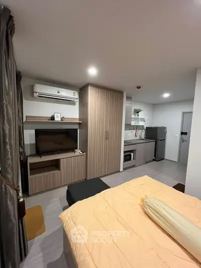 Modern studio apartment with cozy bedroom and compact kitchen area, featuring sleek cabinetry and contemporary design.
