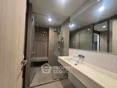 Modern bathroom with glass shower and sleek vanity in contemporary home.