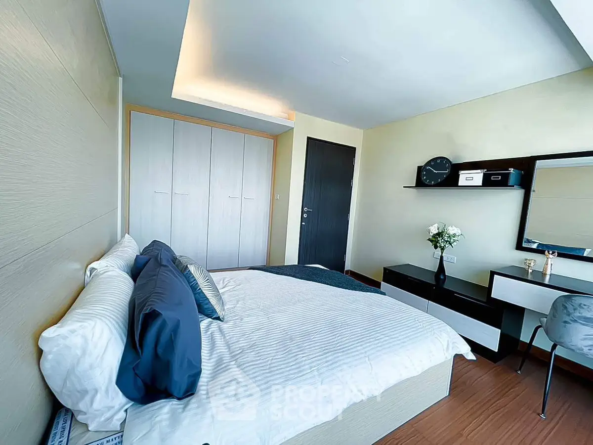Modern bedroom with stylish decor and ample natural light, featuring a cozy bed and sleek furniture.
