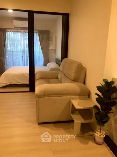 Cozy apartment with a compact living room and bedroom, featuring modern furnishings and natural light.