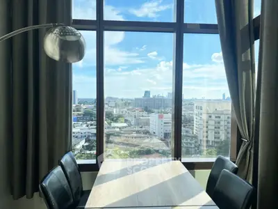 Stunning city view from a modern dining area with large windows and sleek furniture.