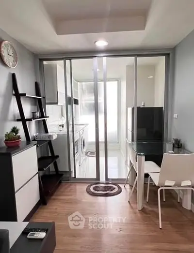 Modern apartment interior with glass partition, wooden flooring, and compact dining area.