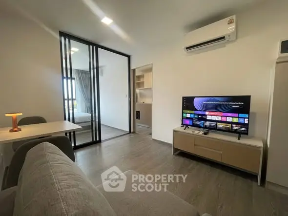 Modern living room with smart TV and sliding glass doors leading to bedroom