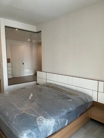Modern bedroom with sleek design and large mirror, featuring a new mattress in a stylish apartment.
