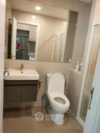 Modern bathroom with sleek fixtures and large mirror in contemporary apartment.