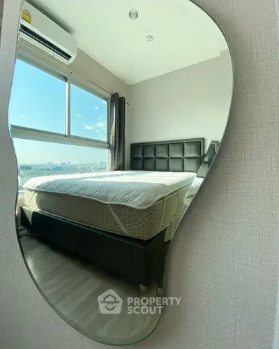 Modern bedroom with stylish mirror reflecting bed and city view, featuring air conditioning and natural light.