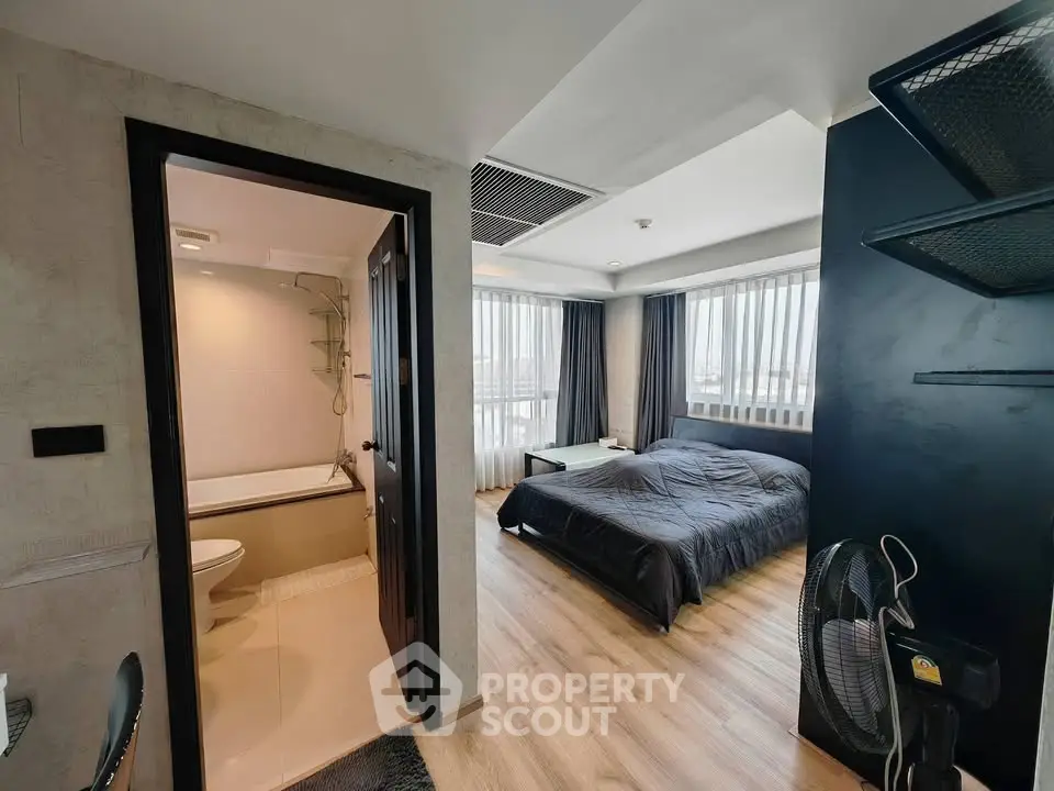 Modern studio apartment with bedroom and bathroom, featuring large windows and sleek design.
