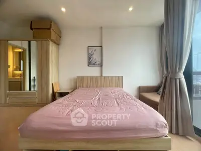 Spacious bedroom with modern decor and large window offering city views.