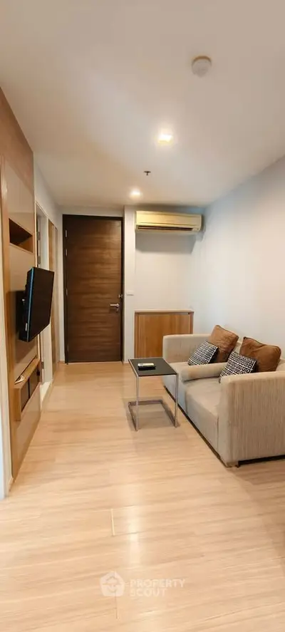 Cozy living room with modern decor and wall-mounted TV in a stylish apartment.
