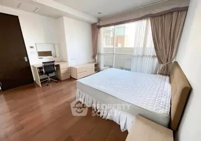 Spacious bedroom with wooden flooring and large window for natural light.