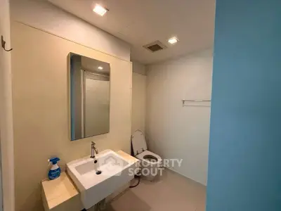 Modern bathroom with sleek sink and toilet, featuring minimalist design and neutral tones.