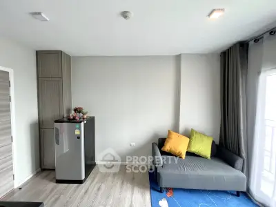 Modern living room with cozy sofa and compact fridge, featuring stylish decor and natural light.