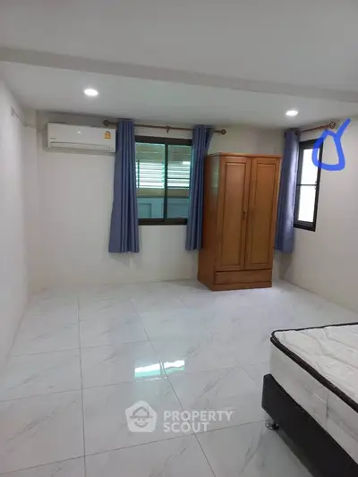 Spacious bedroom with air conditioning and wardrobe, featuring tiled flooring and natural light.