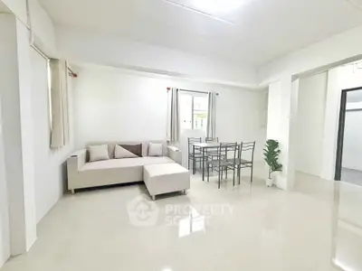 Spacious living room with modern furniture and dining area in a bright, minimalist apartment.