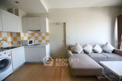 Modern living room with open kitchen, featuring cozy sofa and washing machine.