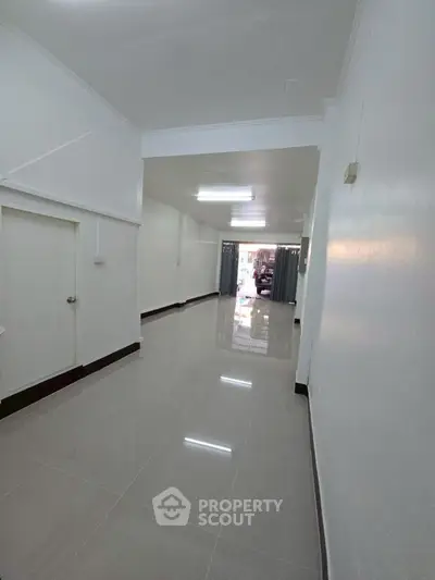 Spacious hallway with glossy tiled floors and bright lighting, ideal for modern living.