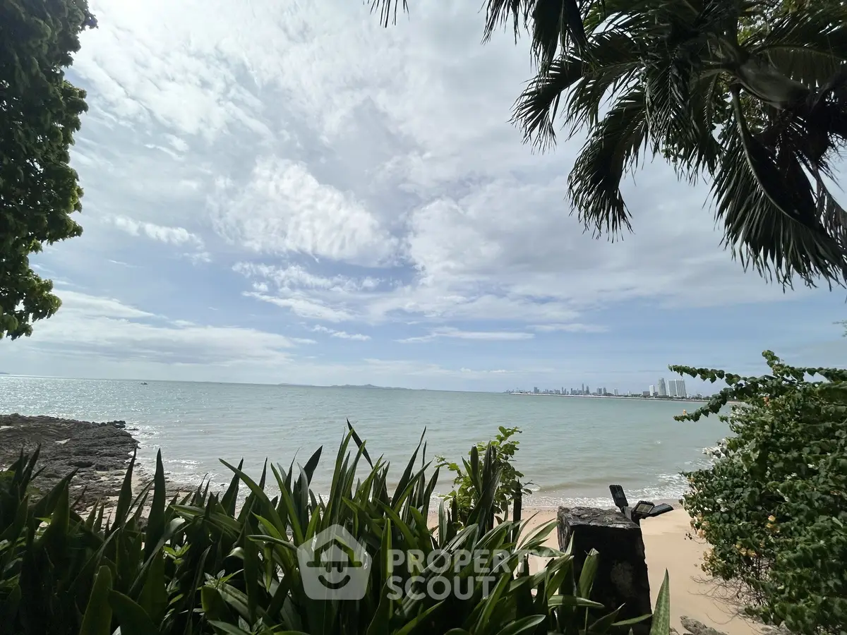 Stunning beachfront view with lush greenery and city skyline in the distance.