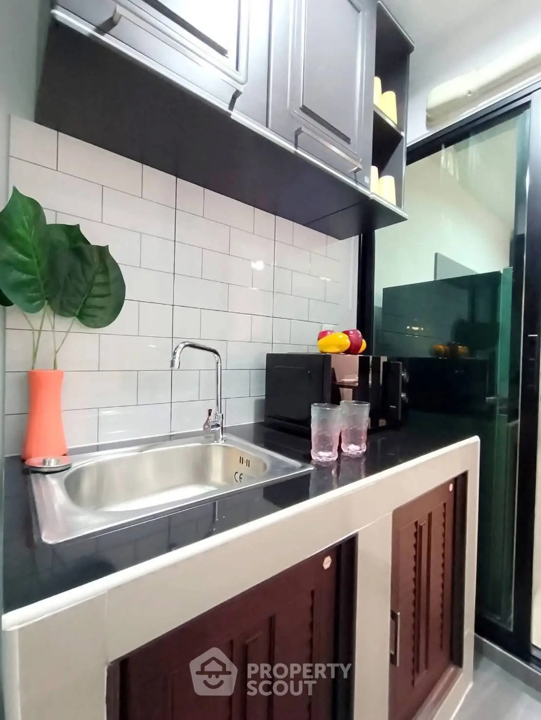 Modern kitchen with sleek cabinetry and stainless steel sink, featuring a stylish backsplash and compact appliances.