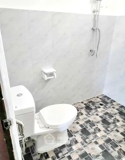 Modern bathroom with tiled walls and floor, featuring a toilet and shower area.