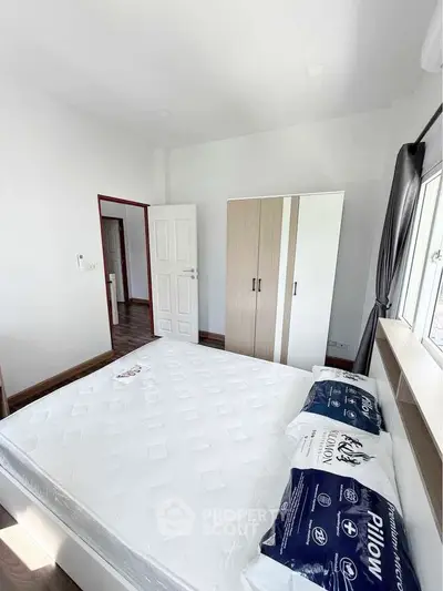 Bright and airy bedroom with large window and modern furnishings.