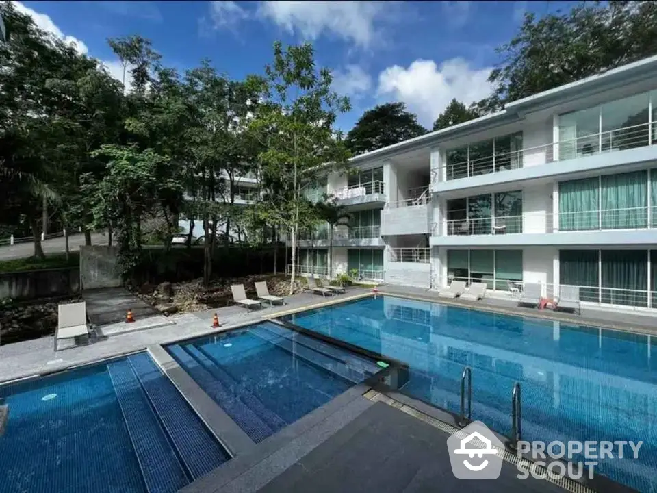 Luxurious modern apartment complex with a stunning outdoor pool and lush greenery.