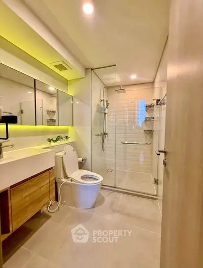 Modern bathroom with glass shower and sleek vanity in contemporary apartment.