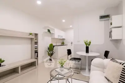 Modern living room with open kitchen, stylish decor, and cozy seating area.