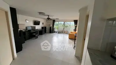 Spacious living room with modern decor and large windows offering natural light and garden view.