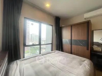 Modern bedroom with large window offering city view, featuring sleek wardrobe and air conditioning.