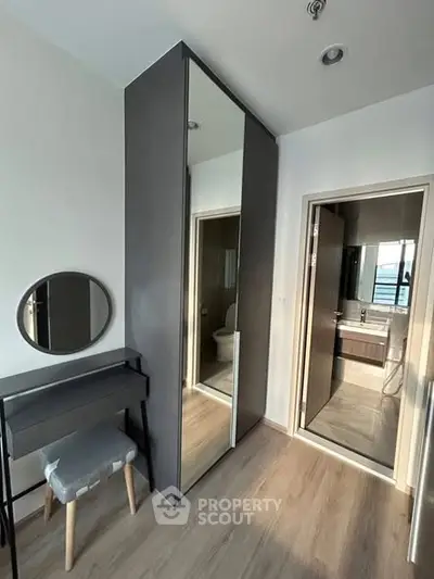 Modern bedroom with sleek wardrobe and ensuite bathroom, featuring stylish furniture and contemporary design.