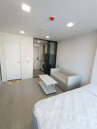 Modern studio apartment with minimalist design, featuring a cozy living area and compact kitchen.