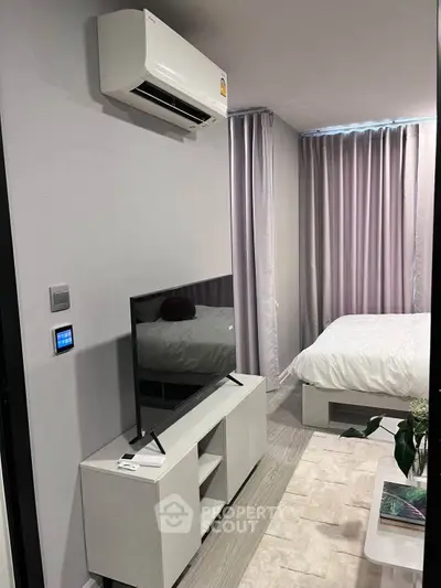 Modern bedroom with sleek TV setup and air conditioning, featuring elegant curtains and stylish decor.