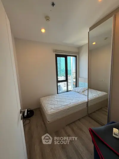 Modern bedroom with city view, featuring a single bed and mirrored wardrobe, perfect for urban living.