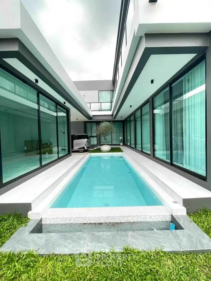 Luxurious modern home with sleek pool and expansive glass windows, perfect for contemporary living.