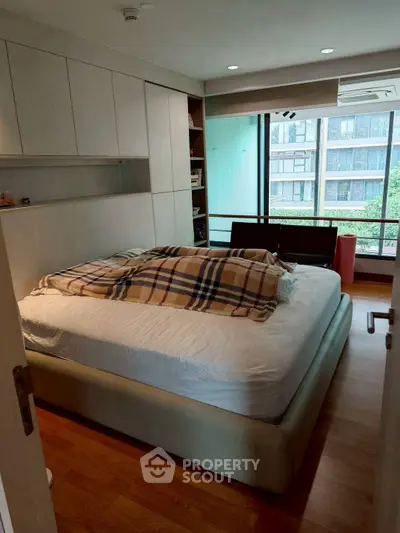 Cozy bedroom with large window and modern furnishings in urban apartment