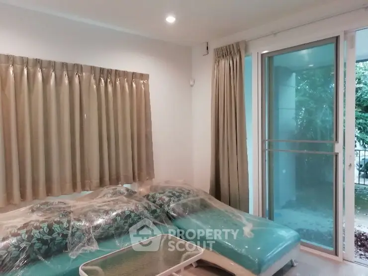 Spacious living room with modern decor and large windows opening to a garden view.