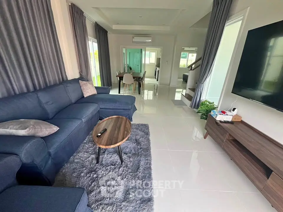 Spacious living room with modern decor and large TV, perfect for family gatherings.