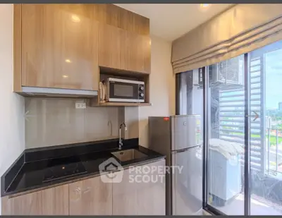 Modern kitchen with sleek cabinets, microwave, and fridge in a compact layout with city view.