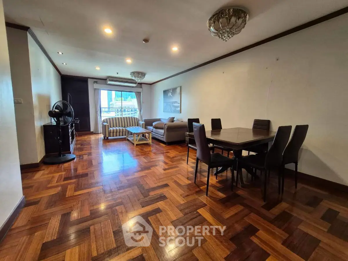 Spacious living room with elegant parquet flooring and modern furniture in a well-lit apartment.