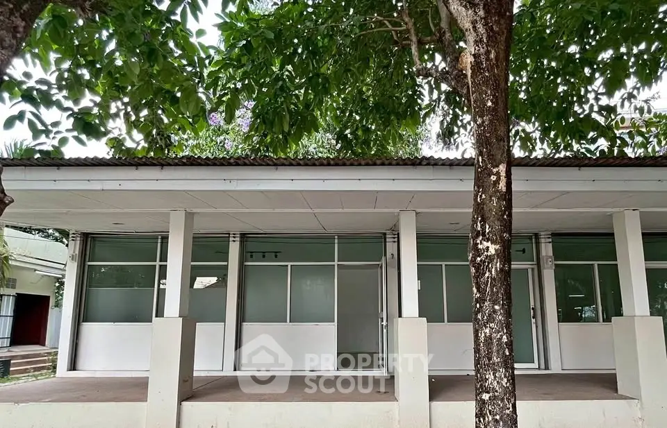 Charming commercial property with large windows and lush greenery, ideal for business opportunities.